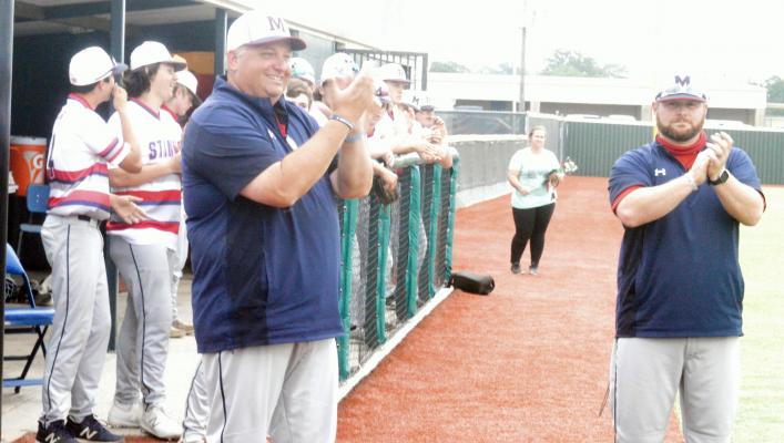 Head MHS baseball coach Adam Borgfeld (left) and assistant coach Anthony Campbell applaud the senior members of the team and their families at MHS on senior night April 27. PHOTO BY CAMPBELL ATKINS