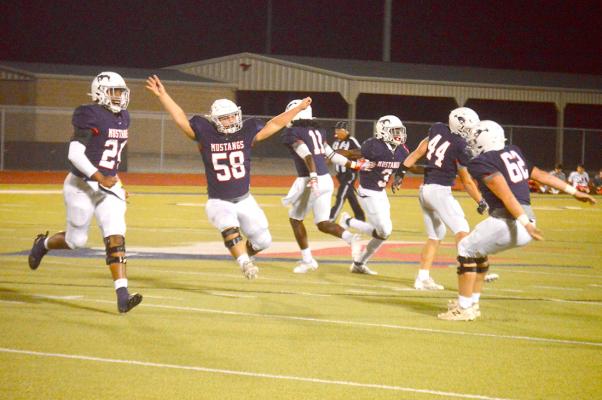 Tyler George (58) prepares to jump into the air and celebrate with teammate Cutter Smith after the Mustangs recovered a fumble deep in Rusk territory in the second quarter Friday. CAMPBELL ATKINS