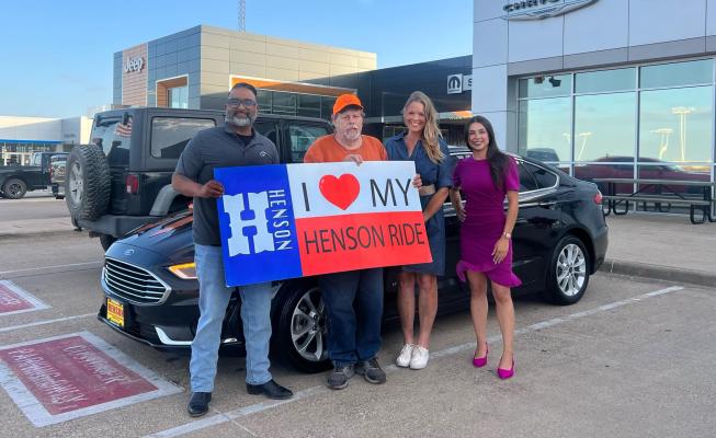 Jeff Little and Robin Baggerley stand with Henson Motors staff members while holding a sign celebrating Little's new vehicle. The dealership donated the car after learning about Little's transportation troubles and his work with Farmers and Hunters Feeding the Hungry through a viral social media post. PHOTO COURTESY OF ROBIN BAGGERLEY
