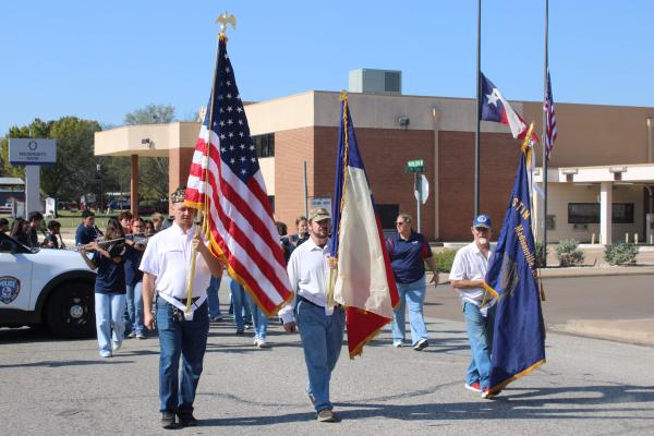 Members of American Legion Austin Reed Post #84 carry the American flag, Texas flag and Legion colors as they lead Saturday's Veterans Day parade through downtown Madisonville while the Mighty Mustang Band follows in formation. 