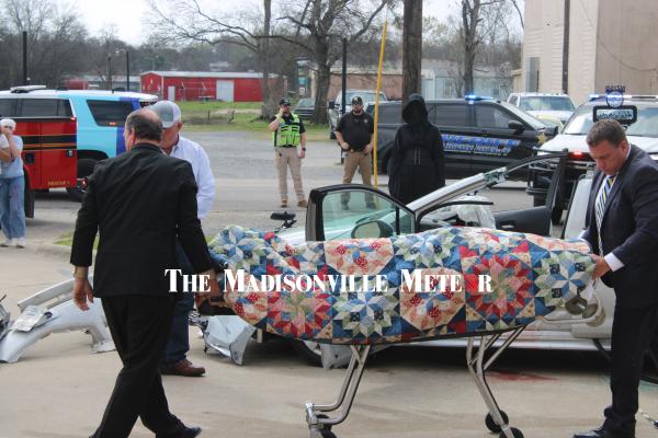 Madisonville Funeral Home staff remove the body of Rylee Spicer from the crash scene as the Grim Reaper looks on during the Shattered Dreams simulation at North Zulch High School Feb. 26.