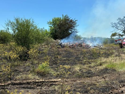 A brush pile burns on an undeveloped 2-acre section at the back of Willowhole Cemetery on Tuesday, May 12. The Willowhole Cemetery Association set the burn after weekend rains, but a wind shift pushed the fire onto surrounding grass. COURTESY PHOTOS