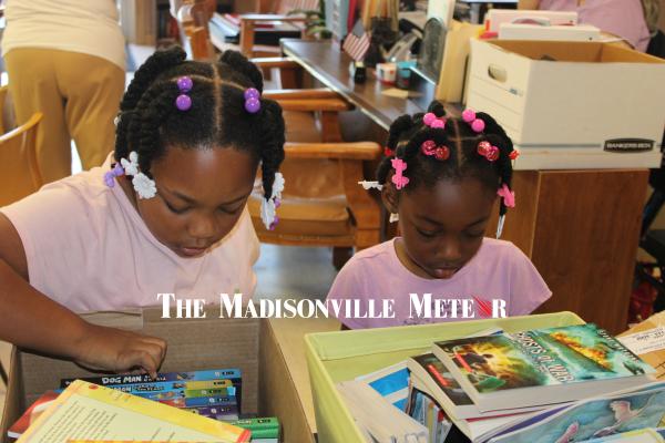 METEOR PHOTO BY RICHARD SIRMAN Autumn and Aubrey Ford, granddaughters of Midway Alderwoman Brenda Ford, search through boxes of donated books Friday at City Hall. The city’s free summer reading program launched May 29 and sends children home with a new book of their own every Friday, running through Aug. 7.
