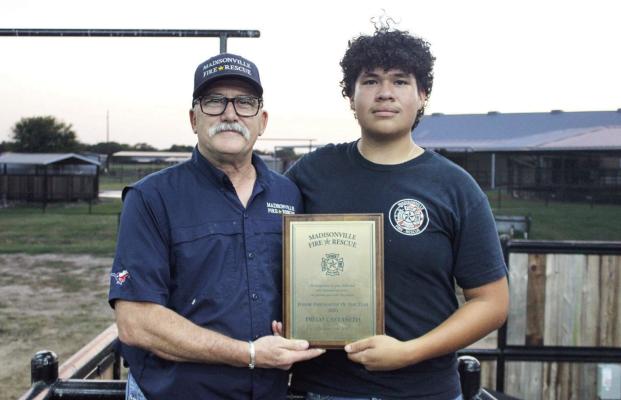 Madisonville Fire Chief Thom Jones, left, delivers the 2025 Junior Firefighter of the Year plaque to Diego Castañeda. The department wanted to present it at the barrel race to mark the celebration. METEOR PHOTOS BY RICHARD SIRMAN
