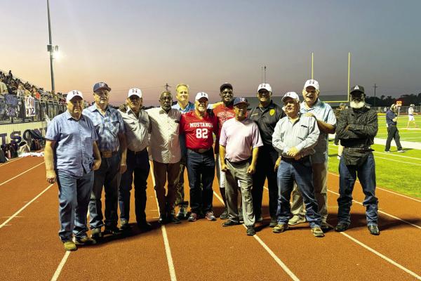 METEOR PHOTOS BY RICHARD SIRMAN AND CAMPBELL ATKINS Twelve members of the 1975 Mustangs gather on the track during the homecoming game at Mustang Stadium. The former players walked behind the team captains for the coin toss, marking the 50th anniversary of their district championship season.