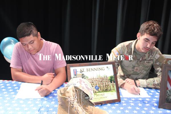 Madisonville High School seniors Bryan Carrion (left) and Gary Bevers sign their enlistment papers during the school’s Military Signing Day, Thursday, May 7. Both will join the National Guard.