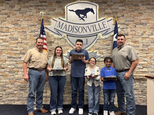 Board Vice President Jason Cleere (left) and board member Bo Williams (right) pose with February students of the month Caitlyn Patin, Donald Soza, Lilliana Roles and Braycen Warfield during the Madisonville Consolidated Independent School District board meeting. Patin represents Madisonville High School, Soza the junior high, Roles the intermediate school and Warfield the elementary campus COURTESY PHOTOS
