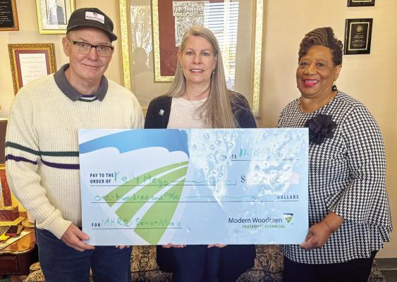 Scott Schmidt (left) with Modern Woodmen Fraternal Financial presents Kelly Mego with the Hometown Heroes award check on Monday, Dec. 15, as Towanda Webber accepts the $100 check as a donation on behalf of the Madison Health Resource Center's Senior Meals Program. Modern Woodmen recognized Mego for her volunteer service and provided a charitable donation to her chosen recipient. METEOR PHOTO BY ANA COSINO-MIZE