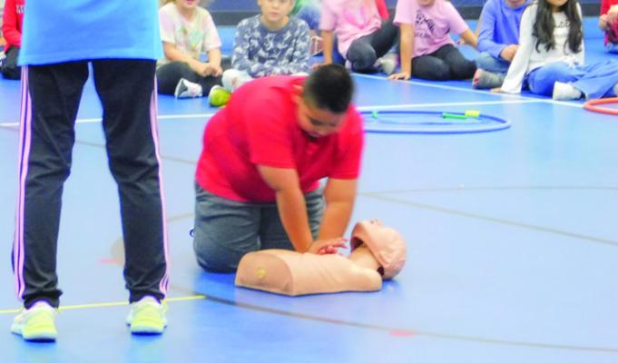 Salvador Hernandez, second grade, demonstrates hands-only CPR on a training dummy during the Kids Heart Challenge.