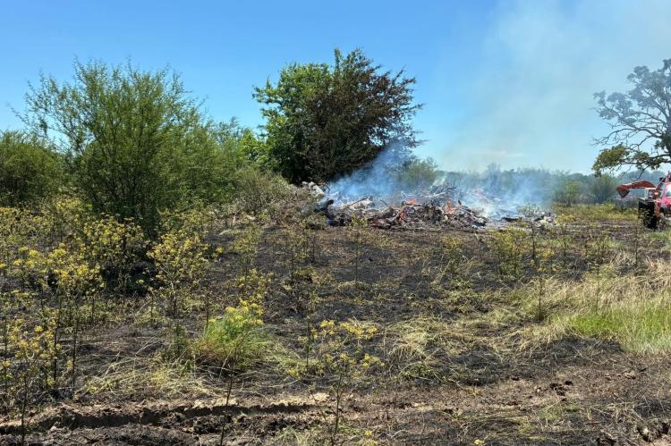 A brush pile burns on an undeveloped 2-acre section at the back of Willowhole Cemetery on Tuesday, May 12. The Willowhole Cemetery Association set the burn after weekend rains, but a wind shift pushed the fire onto surrounding grass. COURTESY PHOTOS