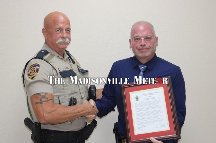 Chief Deputy Curtis Klingle, left, shakes hands with off-duty Montgomery County Precinct 3 Constable’s Office Deputy Walter Dyches after presenting him a Life Saving Award Monday, June 22 at the Madison County Sheriff’s Office. Dyches talked a man down from a Spur 67 overpass on April 30. METEOR PHOTOS BY RICHARD SIRMAN